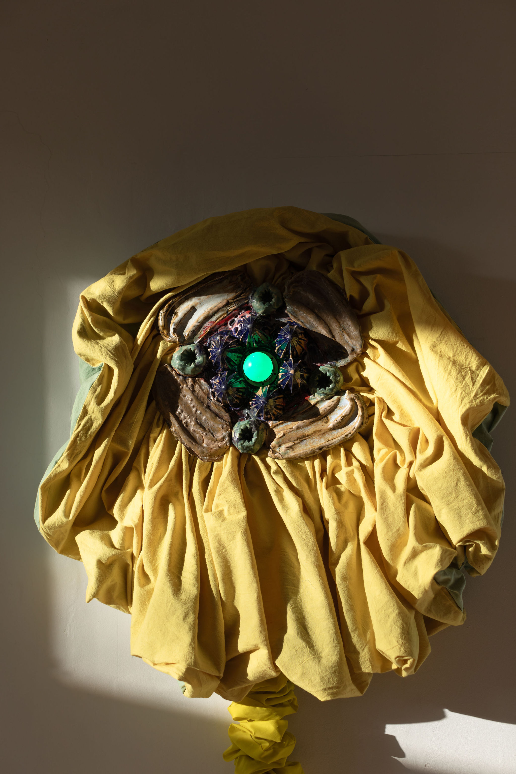  Laura Aldridge, The Inside of Aliveness, 2023. Glazed stoneware, plant dyed fabric (weld and indigo), green bulb, wood, and lighting components. Photo: Caro Weiss. Courtesy of the artist and Kendall Koppe, Glasgow.